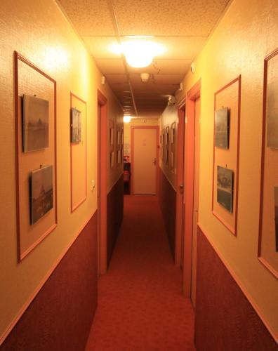 a hallway with a long corridor with pictures on the walls at Logis Hôtel et Restaurant La Tour Brette in Pontorson