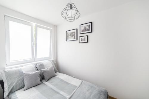 a white bedroom with a bed and a window at Apartament Smętka in Olsztyn