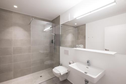 a white bathroom with a toilet and a sink at Airbase Hotel in Kalsdorf bei Graz