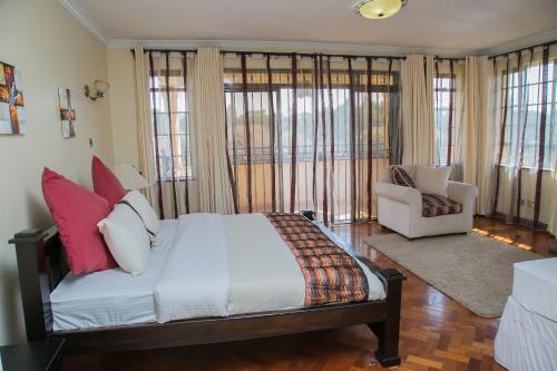 a bedroom with a bed and a chair and windows at Orchid Homes, Gigiri in Nairobi