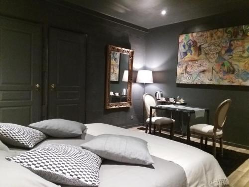 une chambre avec deux lits, un bureau et un miroir dans l'établissement Lorraine Badonviller, à Badonviller