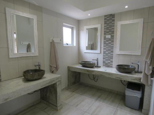 a bathroom with two sinks and two mirrors at Lagoon Chalets in Walvis Bay