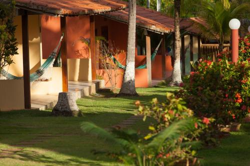 a building with palm trees and plants in a yard at Pousada Praia das Ondas - Pé na areia in Itacimirim