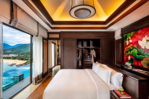 a bedroom with a large bed and a large window at Banyan Tree Lang Co in Lang Co