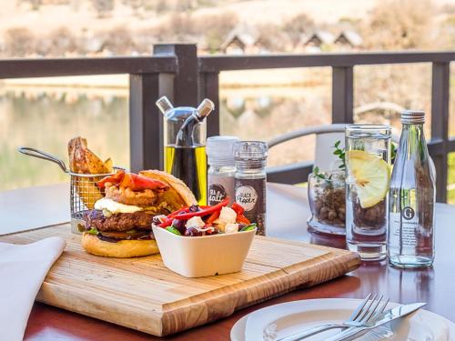 a wooden cutting board with a sandwich and salad on a table at Kloofzicht Lodge & Spa in Muldersdrift