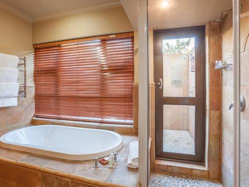 a bathroom with a tub and a window at Kloofzicht Lodge & Spa in Muldersdrift