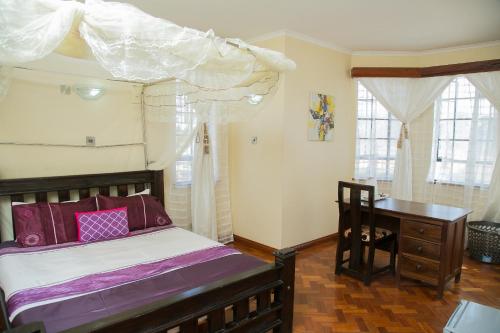 a bedroom with a bed with a canopy and a desk at Orchid Homes, Gigiri in Nairobi