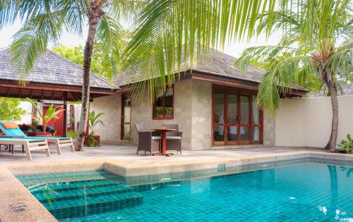 a villa with a swimming pool in front of a house at Kuredu Island Resort & Spa in Kuredu