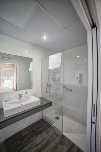 a white bathroom with a sink and a shower at Alojamientos rurales O Acivro in A Rúa