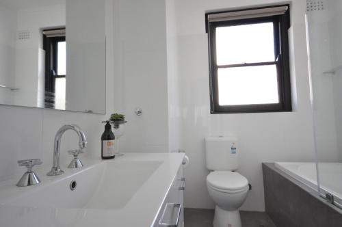 a white bathroom with a toilet and a window at The One @ Henley Beach in Grange