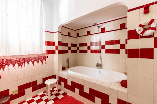W łazience wyłożonej czerwonymi i białymi kafelkami znajduje się wanna. w obiekcie Casa Sole Luna con giardino by Wonderful Italy w mieście Palermo