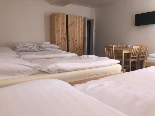 a group of four beds in a room with a table at Penzion Hvězda - Restaurace dočasně uzavřena in Rumburk