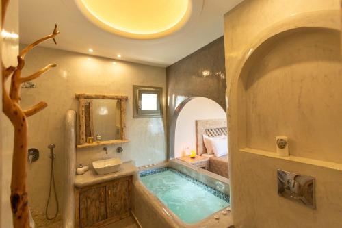 baño con bañera y lavamanos y cama en Elixirium villa en Perissa