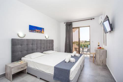 een slaapkamer met een bed, een tv en een balkon bij BELVITA Hotel in Kolimbia