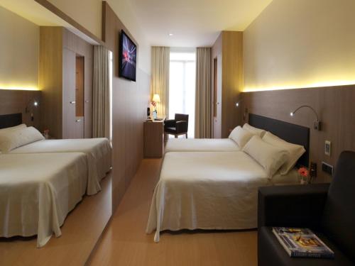 a hotel room with two beds and a desk at Hotel Lleó in Barcelona