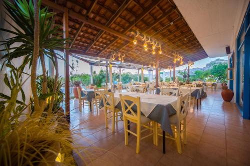 un restaurante con mesas blancas, sillas y plantas en Sea Harmony, en Kalathos