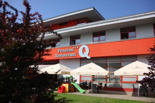 a building with tables and umbrellas in front of it at Penzión***Q in Zvolen