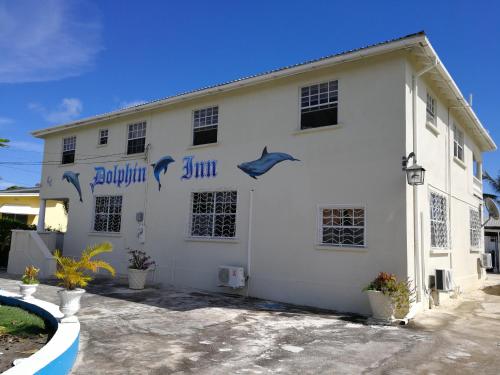 a white building with a dolphin sign on it at Dolphin Inn Guesthouse & Apartments in Christ Church