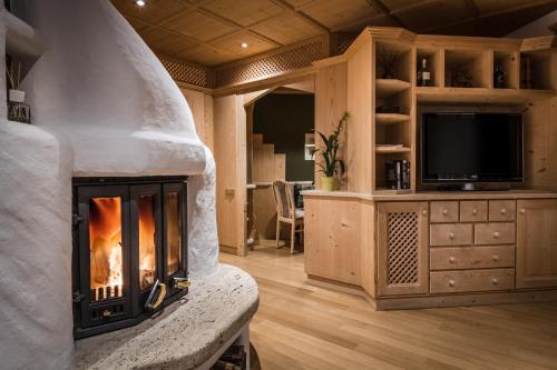 a living room with a fireplace and a tv at Ciasa Scjadu in San Cassiano