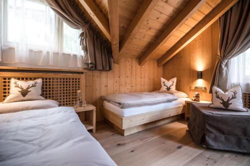 Un dormitorio con dos camas en una habitación con techos de madera. en Ciasa Scjadu, en San Cassiano