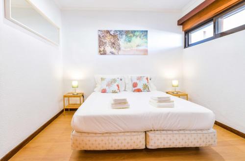 um quarto com uma grande cama branca e 2 janelas em Carcavelos Beach & Business by The Portuguese Butler em Carcavelos