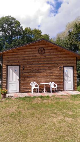 a cabin with two chairs and a table in front of it at White House puhkemaja in Uulu