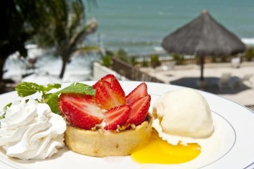 a plate of food with strawberries and ice cream on the beach at Rifoles Praia Hotel e Resort in Natal