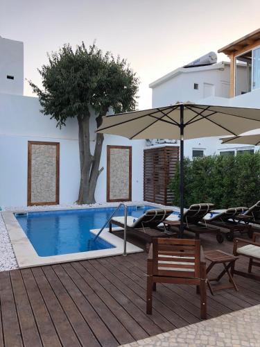 a pool with chairs and an umbrella next to a building at Villa Rio Guest House Suites in Portimão