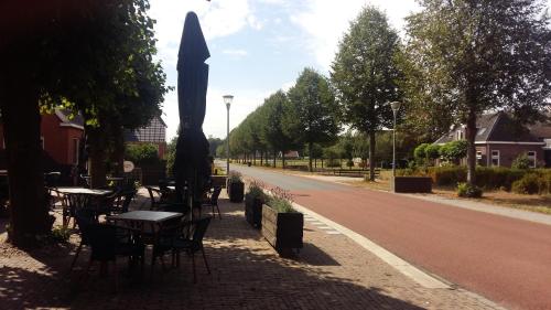 an empty street with tables and chairs and a umbrella at Café Langelo in Langelo