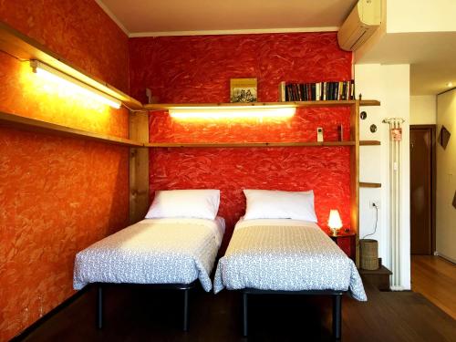 twee bedden in een kamer met een rode muur bij Porta Volta Flexyrent Studio in Milaan