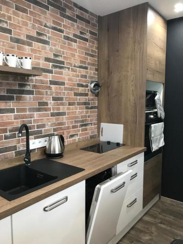 a kitchen with a sink and a brick wall at Apartment Kubo in Vranov nad Topľou