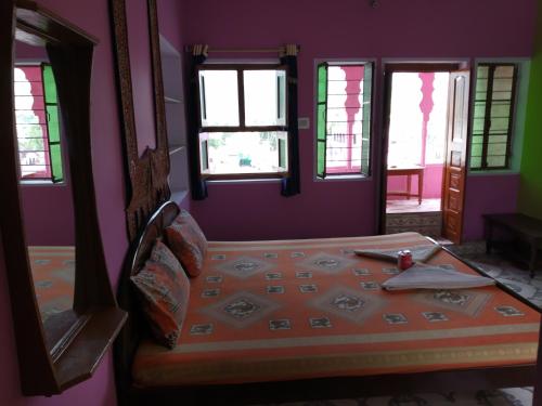 a bedroom with a bed with purple walls and windows at Hotel Paramount Palace in Pushkar