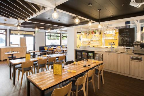 a restaurant with wooden tables and chairs and a bar at ibis Lille Lomme Centre in Lomme