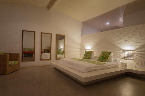 a bedroom with a large bed with three mirrors at Hotel Coucoue Lodge in Assinie