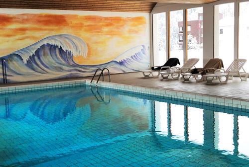 a swimming pool with chairs and a mural of a wave at I dr Rehwiesa C21 in Arosa