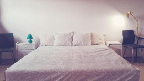 a bedroom with a white bed with two chairs at Voyage in Varaždin