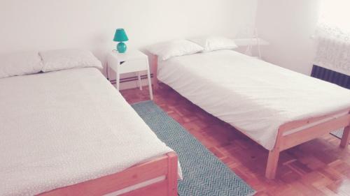 two beds in a room with a green lamp on a table at Voyage in Varaždin
