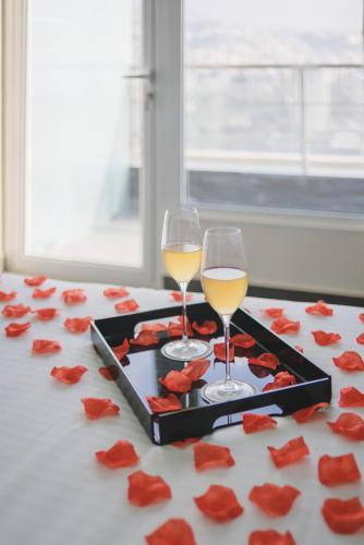 two glasses of white wine and red roses on a table at Louis V Hotel Beirut in Beirut