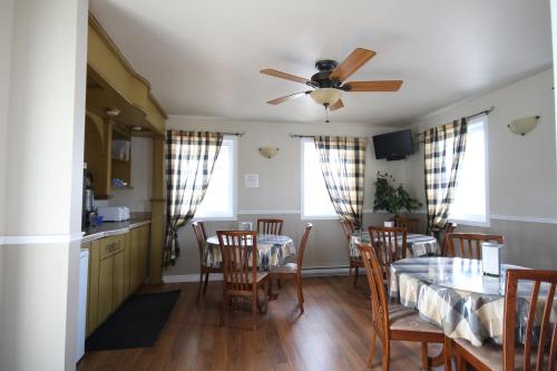 une salle à manger avec une table, des chaises et un ventilateur de plafond dans l'établissement Motel Marie-Dan, à Sainte-Eulalie