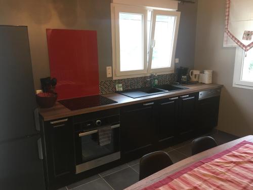 La cuisine est équipée d'un évier et d'une armoire rouge. dans l'établissement la Bergerie, à Jeuxey