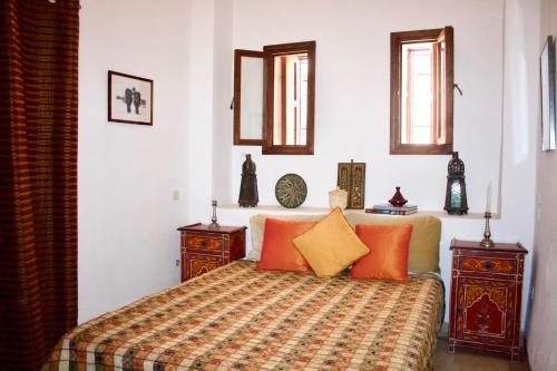 a bedroom with a bed with orange and yellow pillows at Riad Ben Youssef in Marrakesh