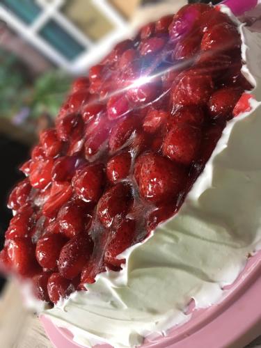 a cake with red berries on top on a pink plate at Lilis kleines Hotel in Münster