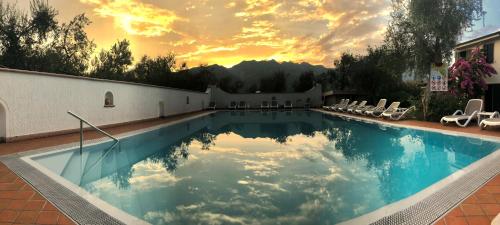 a swimming pool with chairs and a sunset in the background at Residence Alesi in Malcesine