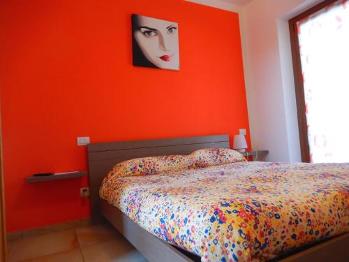 a bedroom with a bed with an orange wall at Le Colline di Maggiora B&B in Maggiora