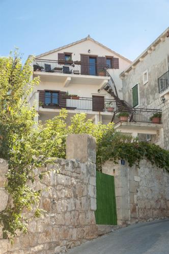 a building behind a stone wall next to a street at Apartment Katija in Postira