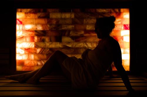 a woman sitting in front of a fireplace at Hotel Königsleiten Vital Alpin in Königsleiten