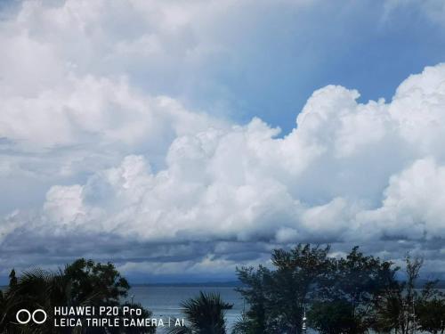 a cloudy sky with trees and a body of water at City Garden Hotel in Tawau