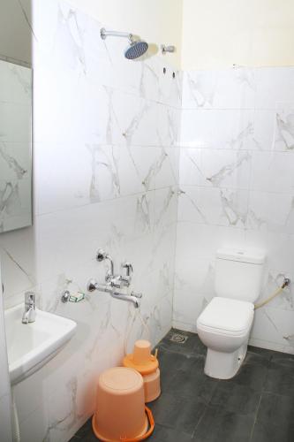 a white bathroom with a toilet and a sink at Mp Residency in Kumbakonam