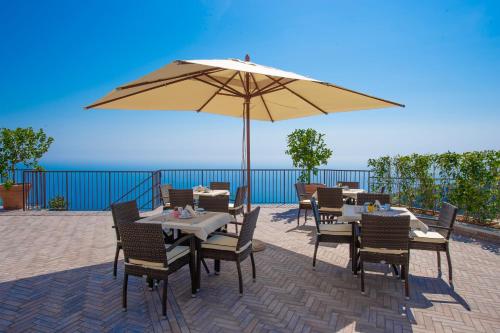 uma mesa e cadeiras com um guarda-sol em um pátio em Villa Paradise Resort em Agerola