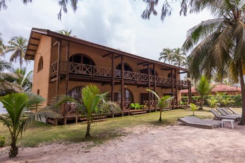 a building on the beach with palm trees in front of it at Hotel Coucoue Lodge in Assinie